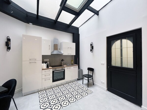 A modern kitchen with white cabinetry, a black stove, and a patterned floor.