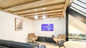 Una sala de estar moderna con techo alto, televisor montado y zona de estar con sofás.