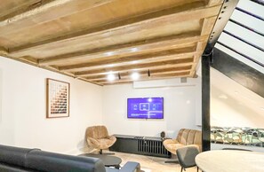 Uma sala de estar moderna com teto alto, TV na parede e área de estar com sofás.