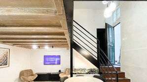 Una sala de estar moderna con vigas de madera a la vista, un televisor de pantalla plana y asientos cómodos.