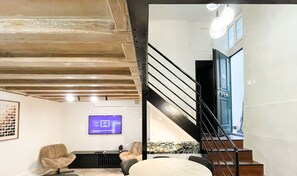 Uma sala de estar moderna com vigas de madeira aparentes, uma TV de tela plana e assentos confortáveis.