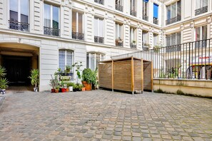 A courtyard with a wooden pergola, potted plants, and a brick pavement.