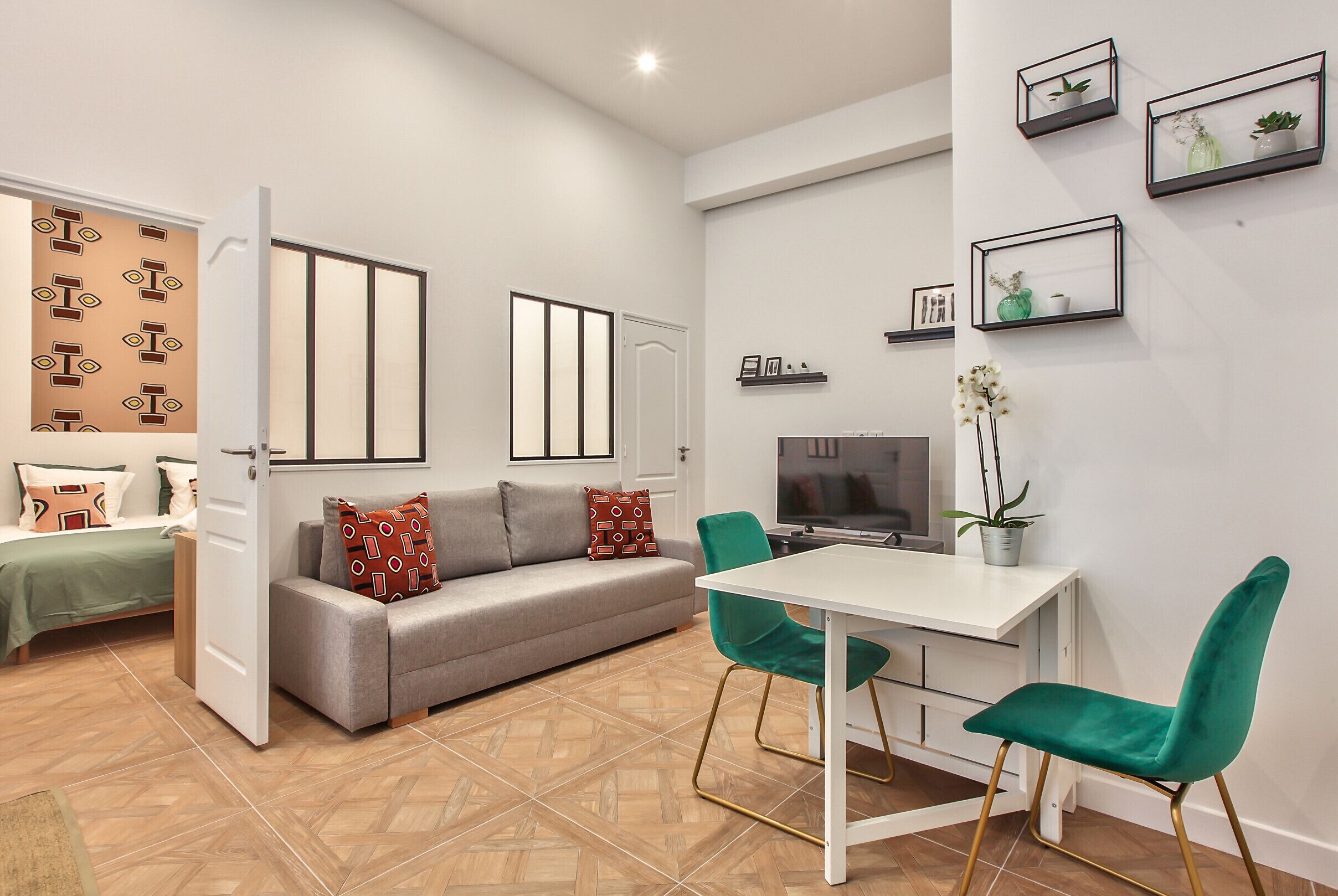 Un salon moderne comprenant un canapé, une table à manger avec des chaises, un téléviseur et des éléments décoratifs sur les murs.
