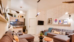 Un salon moderne avec un ensemble de canapés, une table basse et un téléviseur fixé au mur.