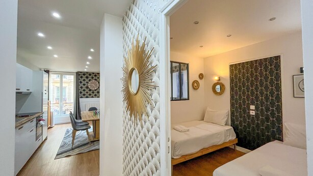 Una camera moderna con un letto, una divisa, un'area pranzo con tavolo e sedie, e un angolo cottura.