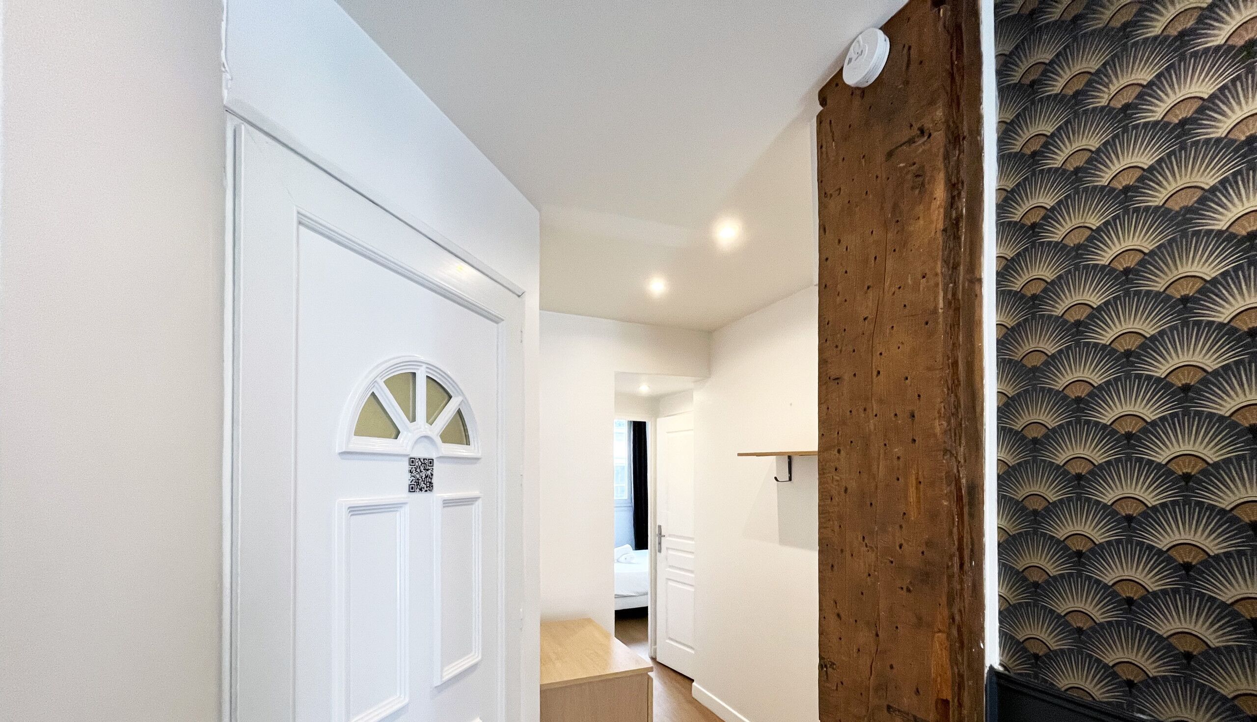 A hallway with a white door, a wooden accent wall, and a patterned wall.