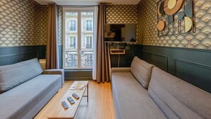 Un salon moderne avec un canapé, une table basse et un téléviseur.