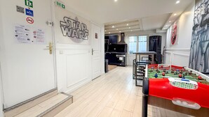 En hotellobby med en vägg dekorerad i Star Wars-stil, ett fotbollsspel och ett köksområde med en grill.