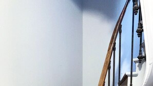 Uma escadaria em espiral com degraus de madeira e balaústres pretos.