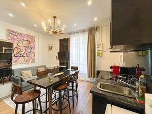 A modern living space with a dining area, kitchen, and a large window with curtains.