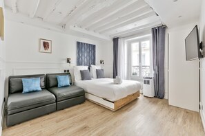 A modern bedroom with a bed, a sofa, a TV, and a window with curtains. - 93 - Luxury Flat in Le Marais (París)