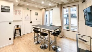 A modern kitchen with a marble countertop, stainless steel bar stools, and a wooden stool.