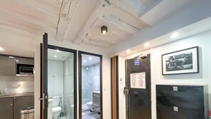 A bathroom with a glass shower enclosure, a toilet, and a sink. There is a door with a sign indicating rules of the building. - Urban Flat 100 - Pretty 2 Bedroom - Beaubourg Marais (París)