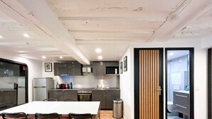 A modern kitchen with a dining area, featuring a large table, chairs, and built-in appliances. - Urban Flat 100 - Pretty 2 Bedroom - Beaubourg Marais (París)