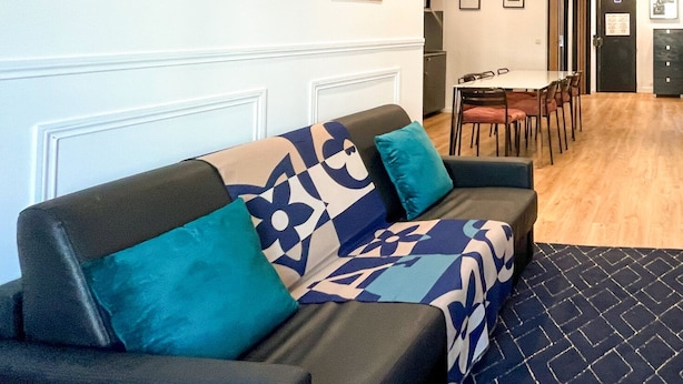 A modern living room with a sofa, a dining table, and a kitchen area. - Urban Flat 100 - Pretty 2 Bedroom - Beaubourg Marais (París)