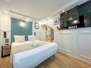 A hotel room with a bed, a TV, a wardrobe, and a patterned wall. - Urban Flat 113 - Pretty 2BDR Flat in Central Paris (París)