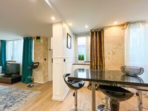 A modern dining area with a glass table, black chairs, a wooden accent wall, and a view of the city. - Urban Flat 113 - Pretty 2BDR Flat in Central Paris (París)