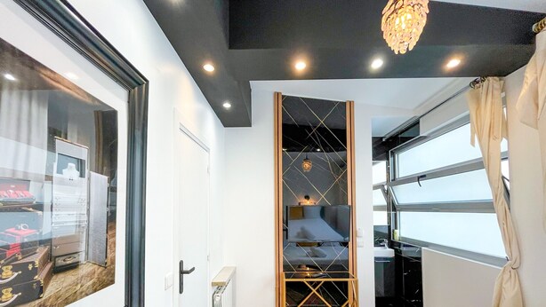 A modern hotel room with a large bed, a wardrobe, a radiator, a TV, and a window with curtains. - Urban Flat 115 A - Louis Fashion Apartment in Paris (París)