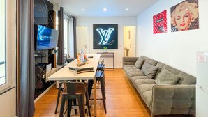 A modern living room with a TV, a table with drinks, a sofa, and wall art. - Urban Flat 115 A - Louis Fashion Apartment in Paris (París)