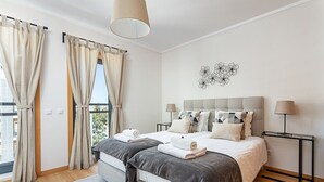 Ein modernes Schlafzimmer mit einem großen Bett, zwei Nachttischen und Blick ins Freie.