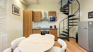 Una cocina compacta con armarios de madera, un microondas, una estufa a gas y una escalera de caracol.