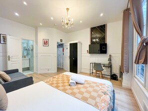Un dormitorio moderno con cama, escritorio, silla y televisor.