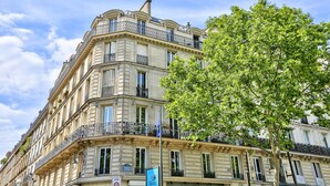 A multi-story building with balconies, large windows, and a tree in the foreground. - Urban Flat 119 - Spacious 5 Bedroom Flat in Paris (Paris)