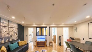 A modern living room with a sofa, a coffee table, a TV, and a dining area with a table and chairs.