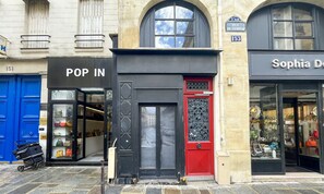 A storefront with a black door and a red door, and a sign that reads "POP IN".