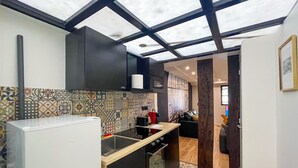 A modern kitchen with a black countertop, a patterned backsplash, and a skylight ceiling.