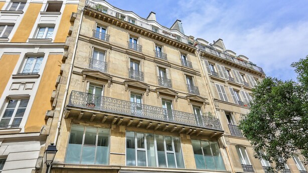 A multi-story building with balconies and large windows.