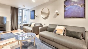 A modern living room with a sofa, armchairs, a coffee table, and a TV.