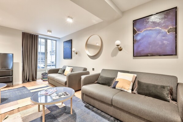 Una sala de estar moderna con un sofá, sillones, una mesa de centro y un televisor.