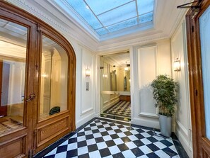 Un couloir d’hôtel avec un sol à carreaux, une porte en bois et une lucarne.