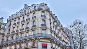 A corner building with multiple balconies, a flag, and a sign indicating a hotel.