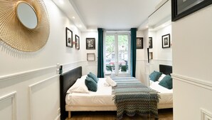 A hotel room with two beds, a large mirror, and framed pictures on the walls.