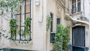 A building with a beige facade, black-framed windows, and potted plants.