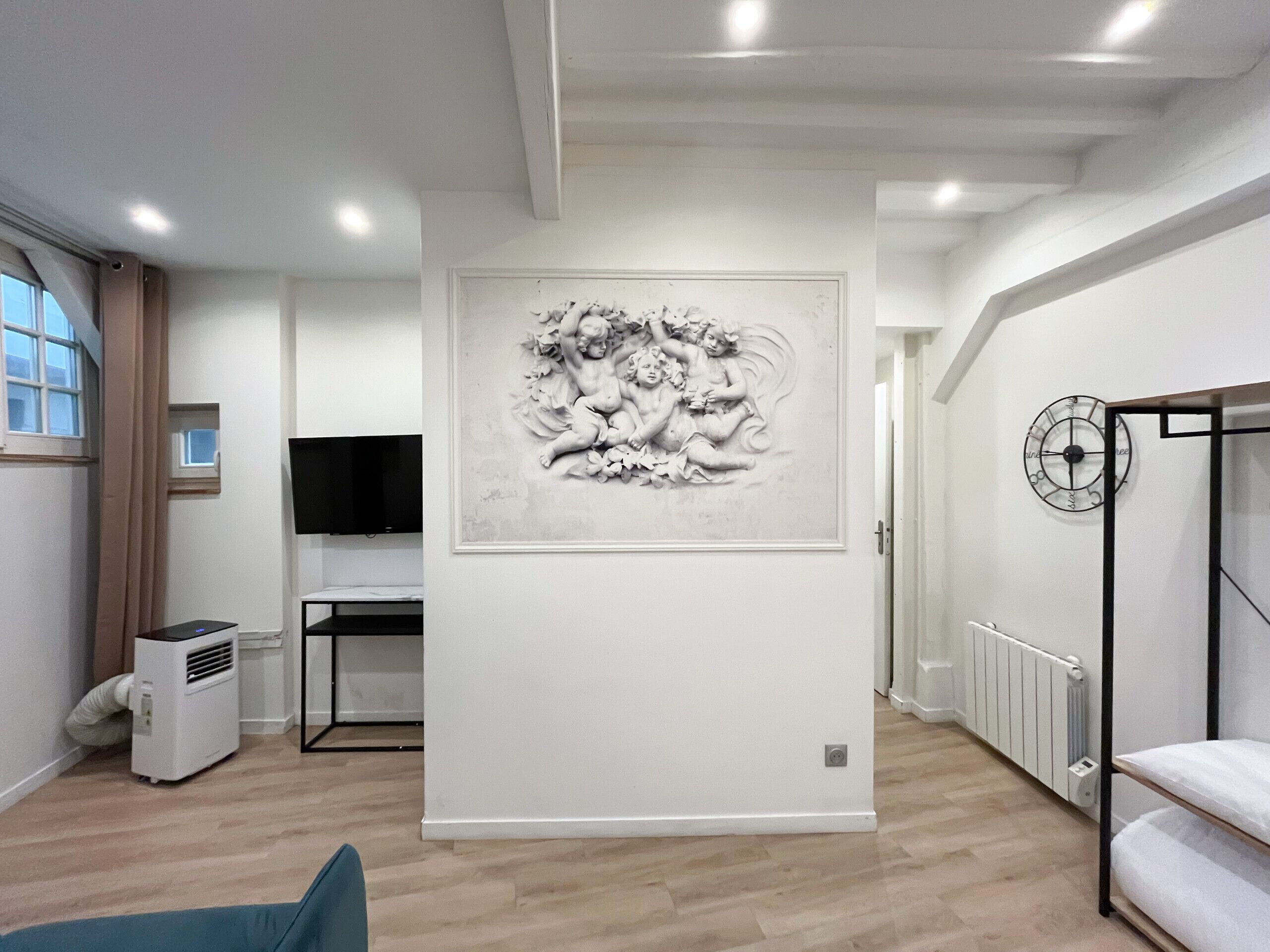 A modern room with a large wall-mounted artwork, a flat-screen TV, a radiator, and a bunk bed.