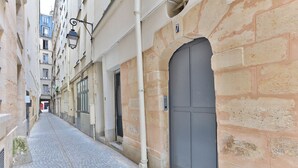 Una estrecha calle adoquinada bordeada por edificios con fachadas de piedra y una gran puerta gris.