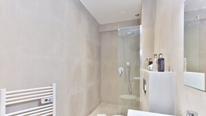 Et moderne badeværelse med bruseniche, toilet i hvidt og et vaskeskab med spejl.