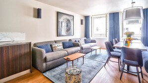 Una sala moderna con un sofá gris, una mesa de centro de madera y un comedor con mesa y sillas.