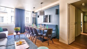 Una sala de estar moderna con un sofá, una mesa de centro y un comedor con sillas y una mesa dispuesta para una comida.