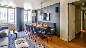 Un salon moderne avec un coin repas, de grandes fenêtres et un canapé gris.