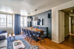 Una sala moderna con comedor, ventanas amplias y un sofá gris.