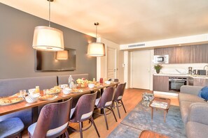 A modern dining area with a long table, chairs, and a kitchen in the background. - 134 - Urban Gorgeous Flat in Montorgueil (París)