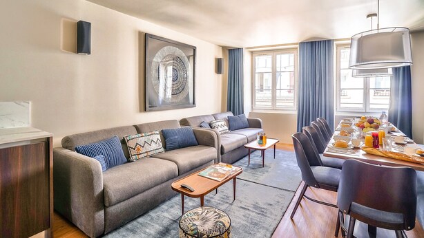 Un salon moderne avec un canapé, une table basse et un coin repas comprenant des chaises et une table mise pour le petit-déjeuner.