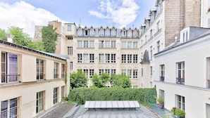 Un cortile con un edificio centrale caratterizzato da numerose finestre e un tetto a punta.
