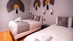 A hotel room with two beds, a wall-mounted fan, and a nightstand. - UrbanFlat 136 - Large Apartment in Paris Center (Paris)