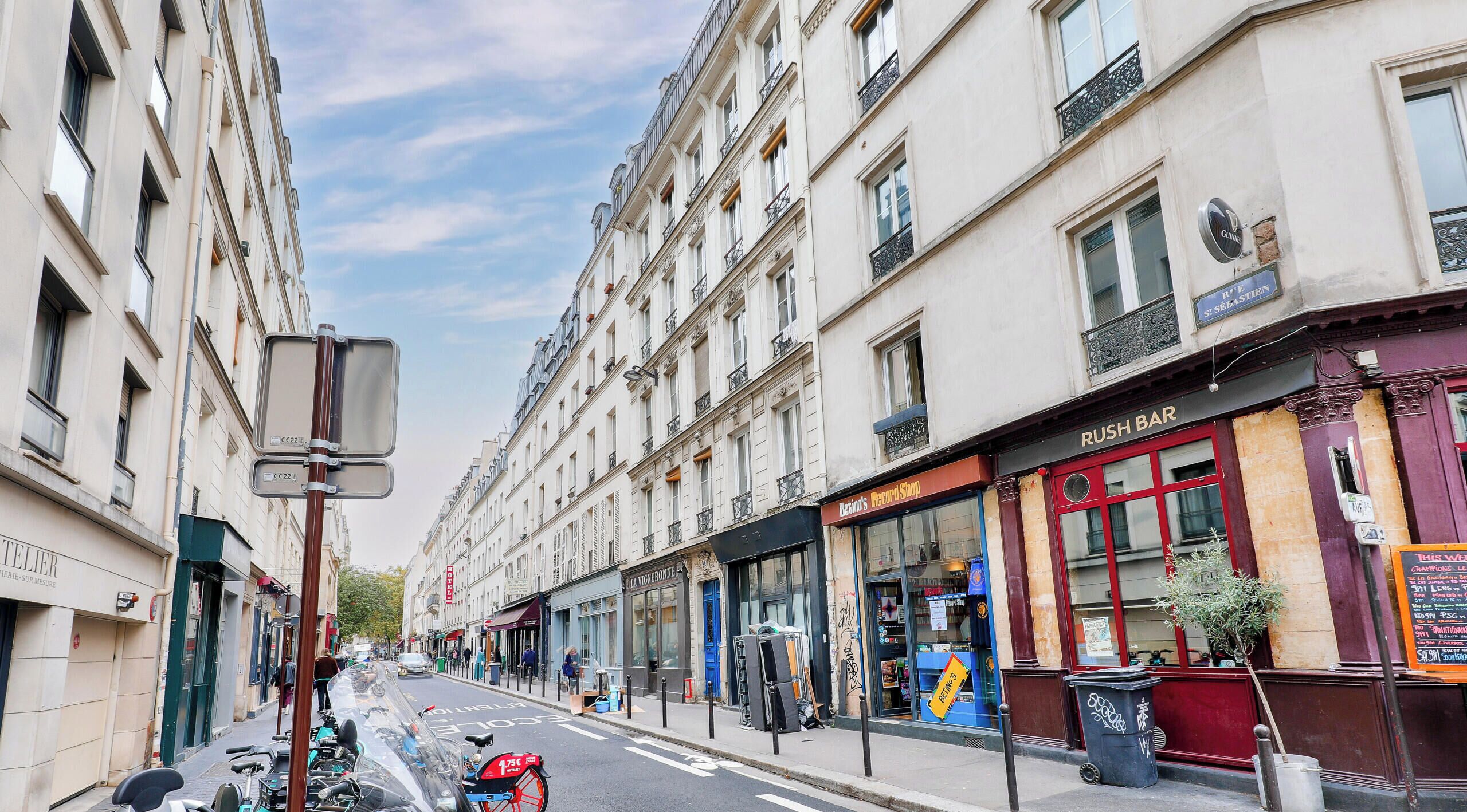 A street view with buildings, a parked motorcycle, and a closed shop with a red awning.