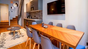 A modern kitchen with a built-in oven, a dining area with a wooden table and chairs, and a staircase leading to another level. - UrbanFlat 136 - Large Apartment in Paris Center (Paris)